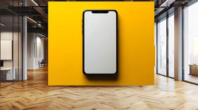  A modern smartphone with a sleek black frame and a blank white screen is displayed against a vibrant yellow background. The phone is centered and viewed from above, emphasizing its minimalist design  Wall mural