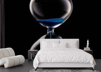 Blue sand hourglass on black background Wall mural