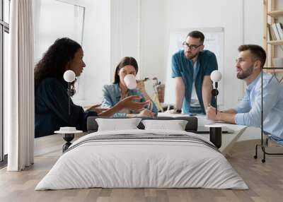 African american businesswoman coaching in boardroom at company meeting. Confident black woman training corporate team at briefing. Young diverse employee share thoughts sit at table. Wall mural