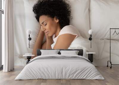 African American woman with hands under cheek sleeping in bed Wall mural