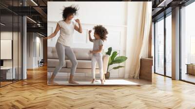 African daughter and mother dancing in modern living room Wall mural