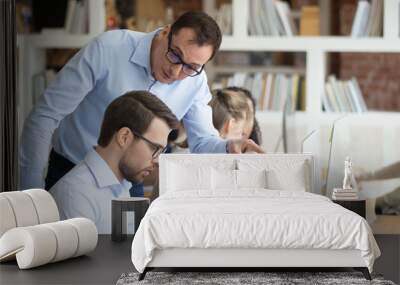 Angry boss criticizing scolding sad male employee for computer mistake Wall mural