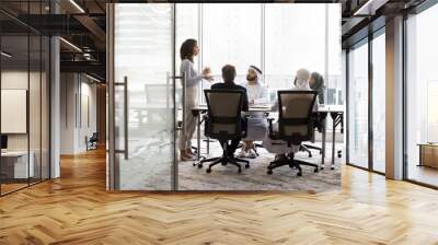 Arabian and European businesspeople discussing collaboration in modern office business meeting room, sitting at large table, talking to standing female group leader. Full length banner shot Wall mural