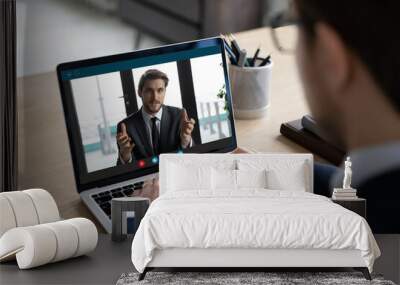 Back view of businessman sit at desk have video call on laptop with male business partner, man employee or boss engaged in webcam conference, brainstorm have team meeting with colleague or client Wall mural