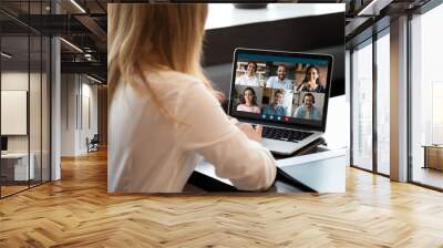 Back view of female employee talk speak on video call on laptop with diverse businesspeople. Businesswoman have webcam digital virtual meeting briefing online on computer with colleagues in office. Wall mural