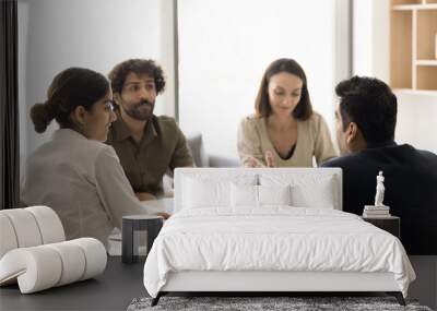 Back view of middle aged Indian businessman talking to team of colleagues, sharing creative idea on brainstorming meeting, discussing project management, teamwork with coworkers Wall mural