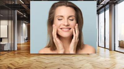 Beautiful smiling young woman with perfect skin touching face Wall mural