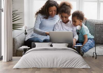 Black family mom with 2 kids using laptop together at home, african american mother teaching children learning computer apps use, explaining online education to focused little son and daughter Wall mural