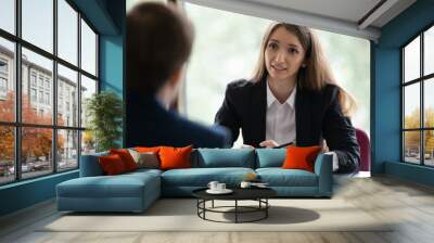 Businesswoman HR manager interviewing male applicant rear view, employer and applicant sit at table opposite each other, answer questions pass job interview. Client and manager talk at meeting concept Wall mural