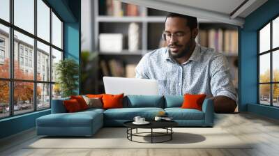 Busy african man freelancer using modern professional app do remote work seated at desk homeoffice cozy room. Employee working typing business e-mail. E-business, e-learning, e-commerce user concept Wall mural