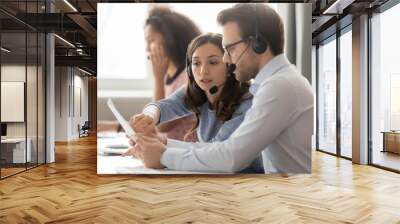 Call center agents in headsets discussing papers helping at workplace Wall mural