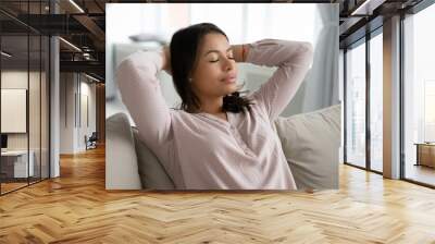 Calm African American young woman sit rest on comfortable couch at home sleep or take nap. Biracial female renter tenant relax on sofa in living room breathe fresh air relieve negative emotions. Wall mural