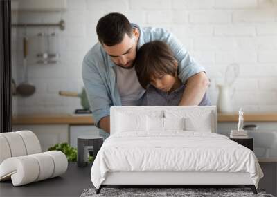 Caring father teaches his son to cook vegetable salad Wall mural