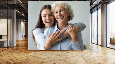 Cheerful affectionate two age generation women embracing indoors, family portrait Wall mural