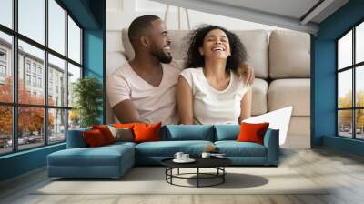 Cheerful african couple having fun using online websites at home Wall mural