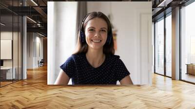 Cheerful confident student, intern girl in wireless headphones head shot portrait. Positive young woman talking on video call, attending online conference, speaking, looking at camera Wall mural