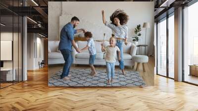 Cheerful couple with little kids having fun dance in living room feel carefree, looking overjoyed having festive mood celebrate relocation day to new own house. Tenancy, family leisure at home concept Wall mural