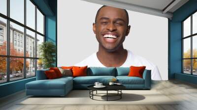 Cheerful happy african millennial man laughing looking at camera isolated on studio blank background, funny young black guy with healthy teeth beaming orthodontic white wide smile head shot portrait Wall mural