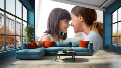 Close up beautiful happy mother and daughter touching with foreheads looking at each other with love tender and devotion, mom expressing support understanding candid emotions sitting on couch at home Wall mural