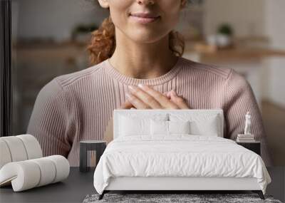 Close up cropped view young attractive Hispanic woman stand alone indoor put folded palms on chest feeling grateful and appreciation, express sincere feelings. Believe, charity, body language concept Wall mural