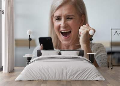 Close up excited older woman shouting, using phone, celebrating success Wall mural