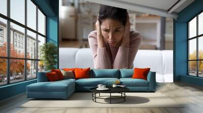 Close up frustrated depressed woman holding head in hands, crying, sitting on couch at home alone, upset unhappy young female lost in thoughts about break up or divorce, psychological problems Wall mural