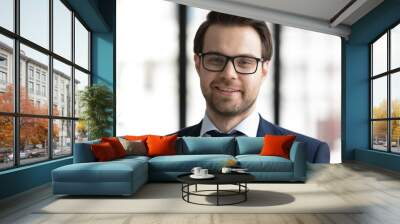 Close up headshot portrait of smiling young Caucasian businessman in formal suit and glasses pose in office, happy successful confident male leader in spectacles show power and motivation at workplace Wall mural