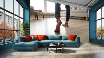 Close up of woman walking barefoot on warm wooden floor Wall mural