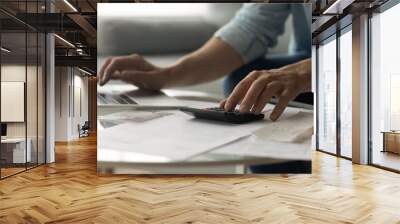 Close up of young male accountant hands make audit of expenses calculate charges based on paper documents. Cropped shot of man bookkeeper work with bills pay fees taxes online using web app on laptop Wall mural