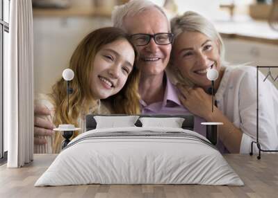 Close up portrait of multi-generational relatives people, pretty mature woman hugs her elderly father sit on sofa with adolescent daughter smile look away. Understanding, care, family ties and unity Wall mural