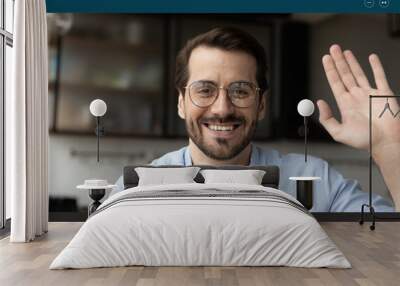 Close up screen view portrait of smiling Caucasian man wave greet speaking on video call at home. Happy European male in glasses have fun engaged in webcam virtual digital conference or online talk. Wall mural