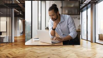 Close up thoughtful African American businessman looking at laptop screen, touching chin, pondering strategy, standing near desk, reading business email, entrepreneur pondering project strategy Wall mural