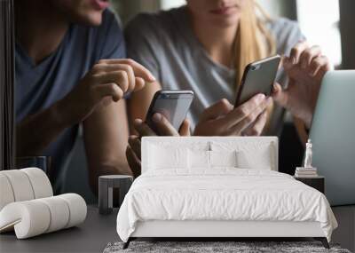 Close up view of man and woman using smartphones discussing mobile apps concept, couple talking holding cellphones synchronizing information online with laptop, checking news or texting messages Wall mural