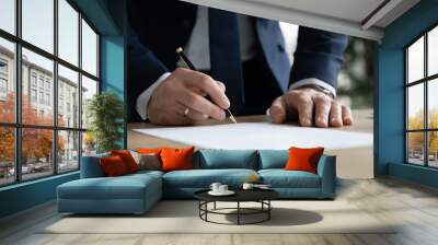 Close up young businessman standing near table with pen in hands, ready signing profitable offer agreement after checking contract terms of conditions, executive manager involved in legal paperwork. Wall mural