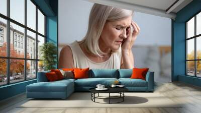 Closeup tired aged woman touches face with hand having migraine Wall mural