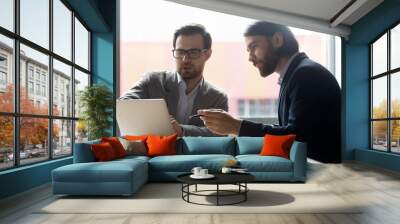 concentrated male colleagues sit at office desk brainstorm work on laptop together, serious focused  Wall mural