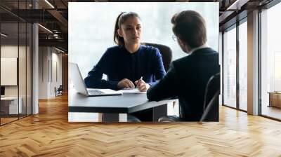 Confident attentive businesswoman hr manager listening to candidate answering questions on job interview, focused recruiter employer looking at applicant, sitting at desk in office Wall mural