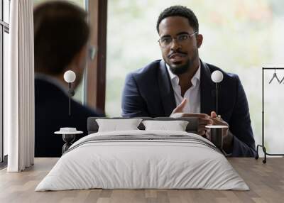 Confident concentrated African American male employee talk with colleague explain thought or idea, focused biracial businessman speak with coworker or partner, brainstorm at office boardroom meeting Wall mural