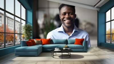 Confident smiling young african businessman looking at camera in office Wall mural