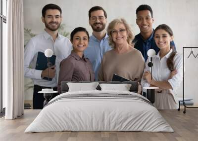 Corporate portrait smiling diverse employees team standing in office, looking at camera, successful happy workers with middle aged leader posing for photo, motivated staff, workforce Wall mural