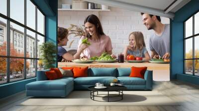 Couple with children sitting at kitchen countertop preparing healthy dinner Wall mural