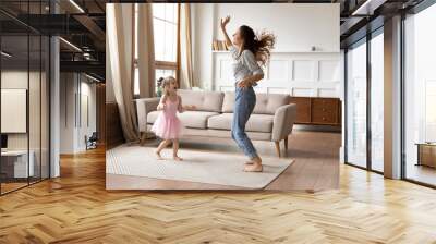 Crazy energetic family of two dancing in living room. Wall mural