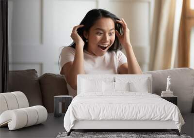 Crazy excited asian woman sit on couch read news online on laptop feels shocked amazed and surprised. Unbelievable sell-out web-store discounts, on-line lottery win, new free cool application concept Wall mural