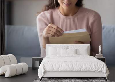 Crop close up of young Caucasian woman hold paper envelope open read postal mail letter at home, female receive post paperwork or document, consider notice or notification correspondence news Wall mural