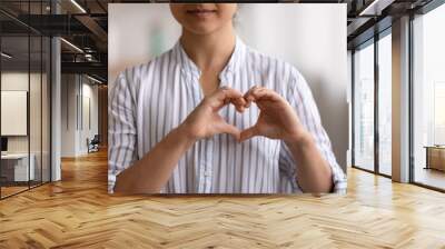 Cropped portrait of young female cardio patient expressing sincere gratitude appreciation to cardiologists volunteers charity givers. Close up of millennial woman posing to camera showing finger heart Wall mural