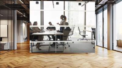 Diverse business group meeting at table in modern urban office, listening to young female African American leader, discussing work project, planning cooperation, teamwork. Through glass view Wall mural