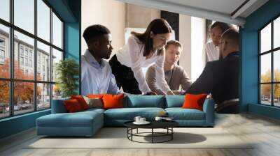 Diverse colleagues working on project together, sitting at table in boardroom, working with legal documents, financial report with statistics, employees engaged in teamwork at corporate meeting Wall mural