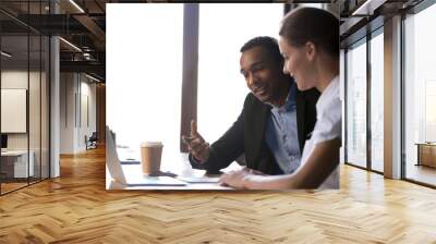 Diverse female male coworkers sitting at desk brainstorming together Wall mural