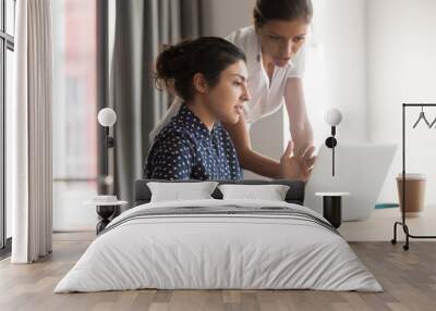 Diverse female mentor and intern talking pointing on laptop Wall mural