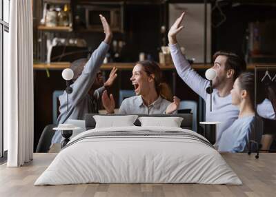 Diverse friends celebrate victory watch game on laptop in cafe Wall mural